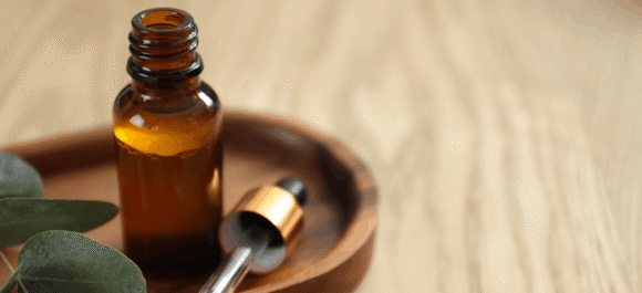 aromatherapy-bottle-essential-oil-eucalyptus-leaves-wooden-table-closeup-space-text